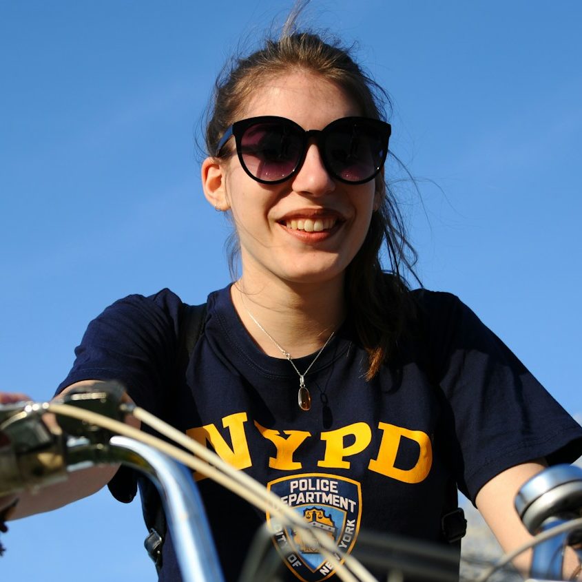 woman in black and yellow crew neck t-shirt riding bicycle during daytime